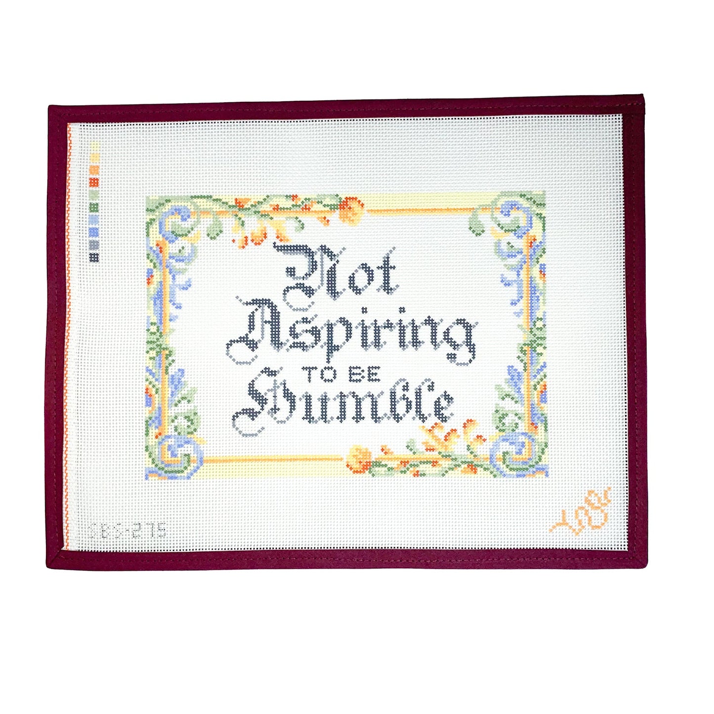 Hand-painted needlepoint canvas featuring the phrase “Not Aspiring to Be Humble” in gothic calligraphy with an ornate floral border, shown in full view on white background.