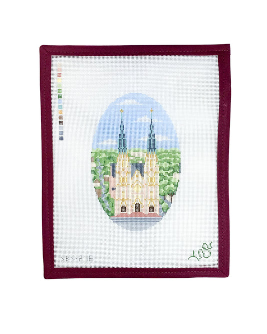 Hand-painted needlepoint canvas featuring the Cathedral-Basilica of St. John the Baptist in Savannah, framed by lush greenery and a blue sky, designed by Spellbound Stitchery.
