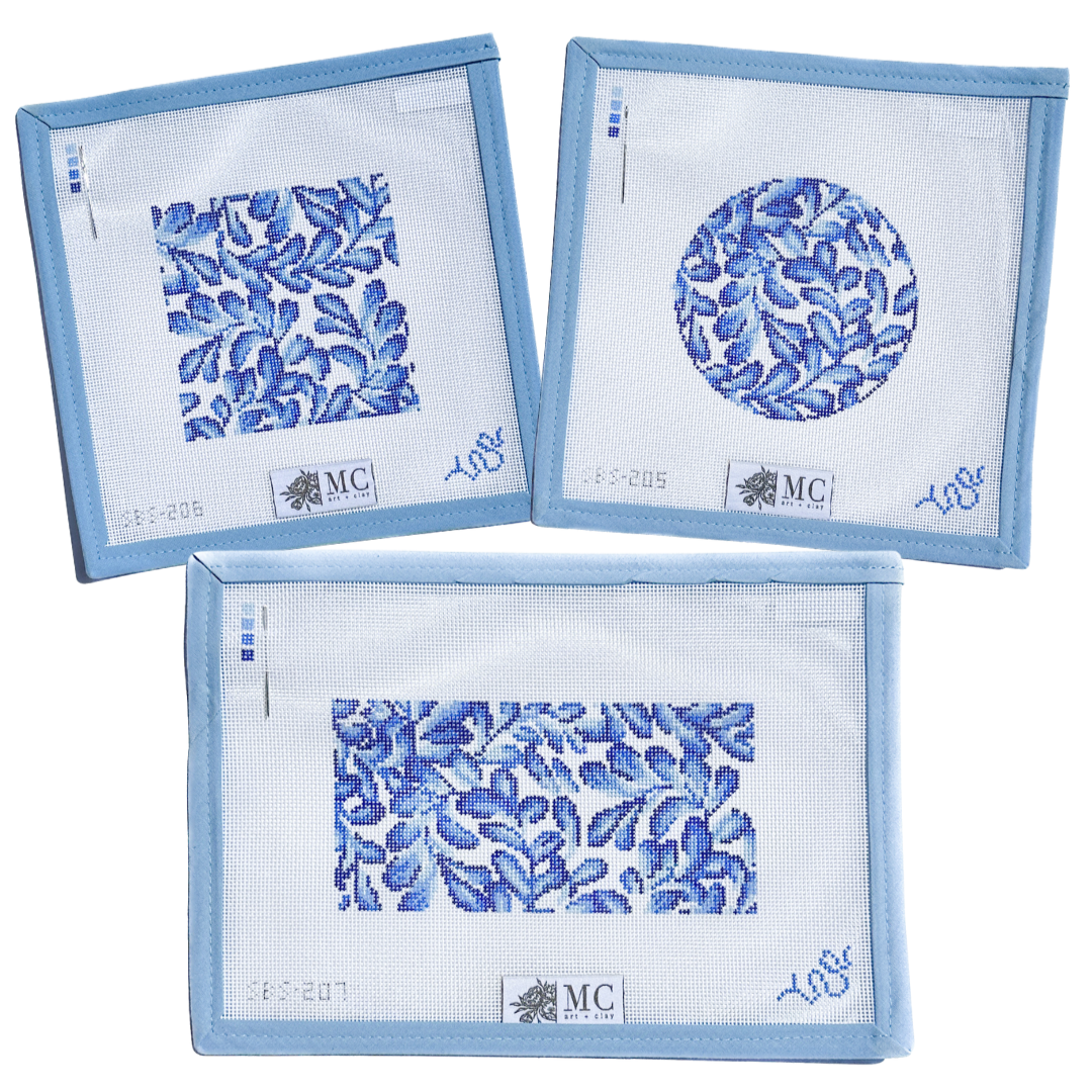 Set of three blue floral patterned needlepoint canvases with 'MC' branding on a white background